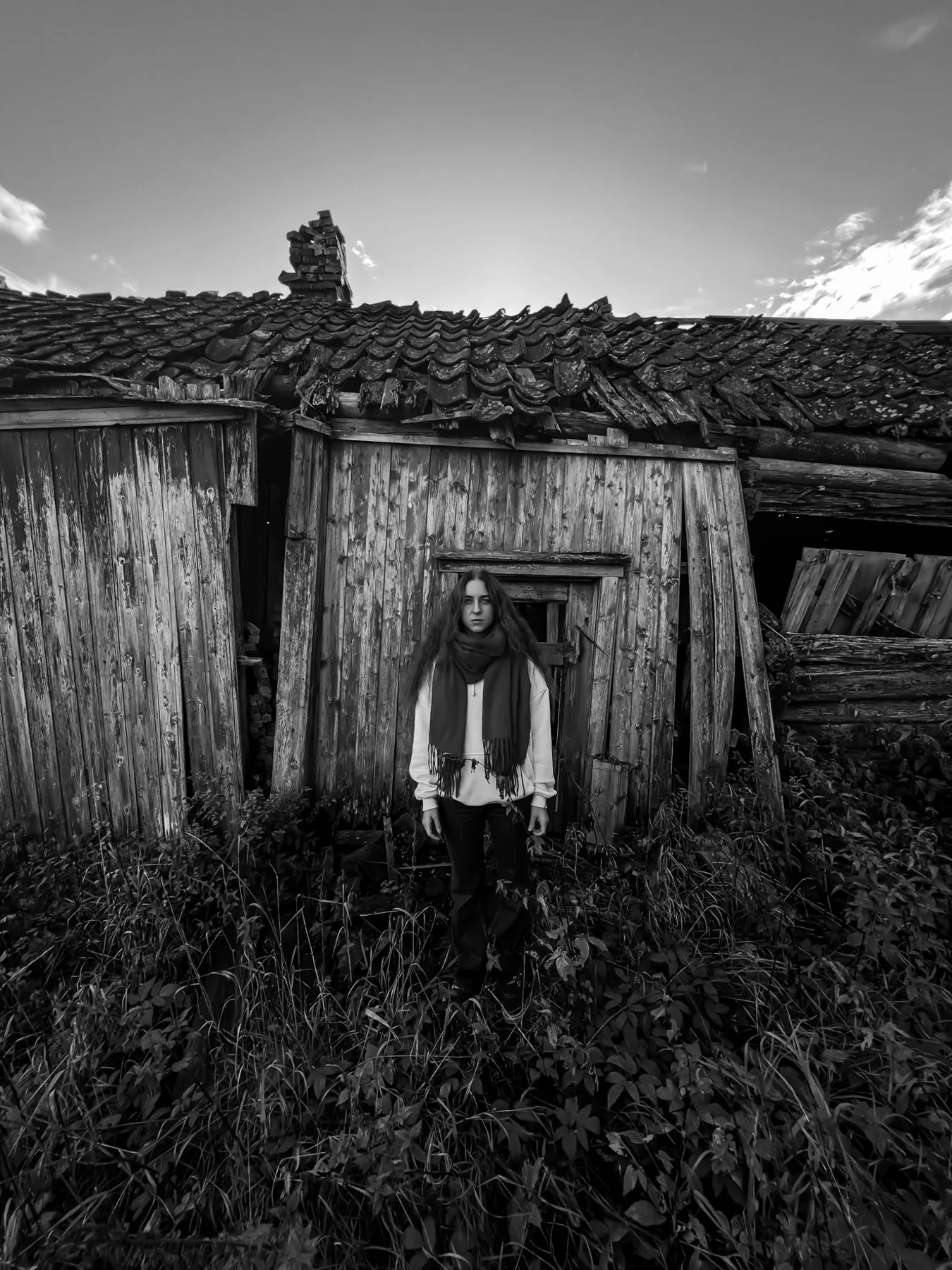 Svart-hvitt-portrett foran et værbitt trehus