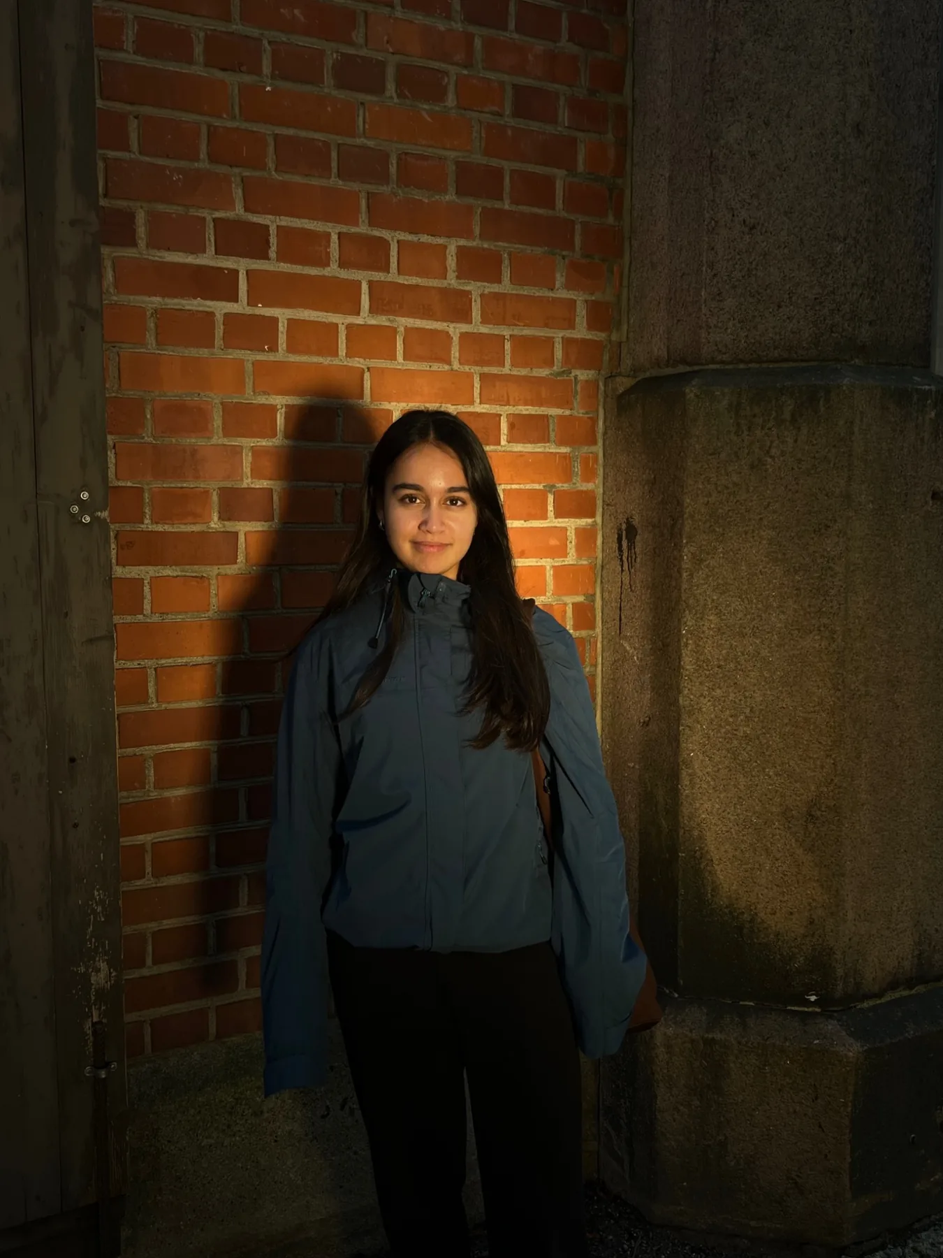 Portrett mot en murvegg i varmt kveldslys